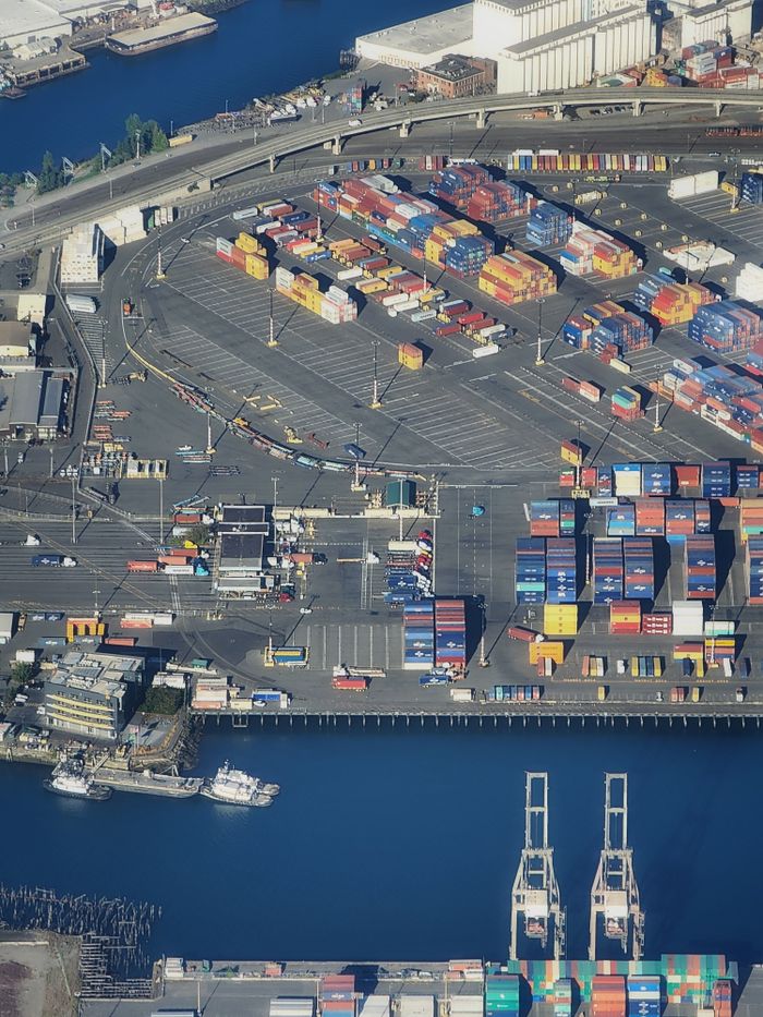 Overhead view of a bustling port with colorful shipping containers and waterfront area.