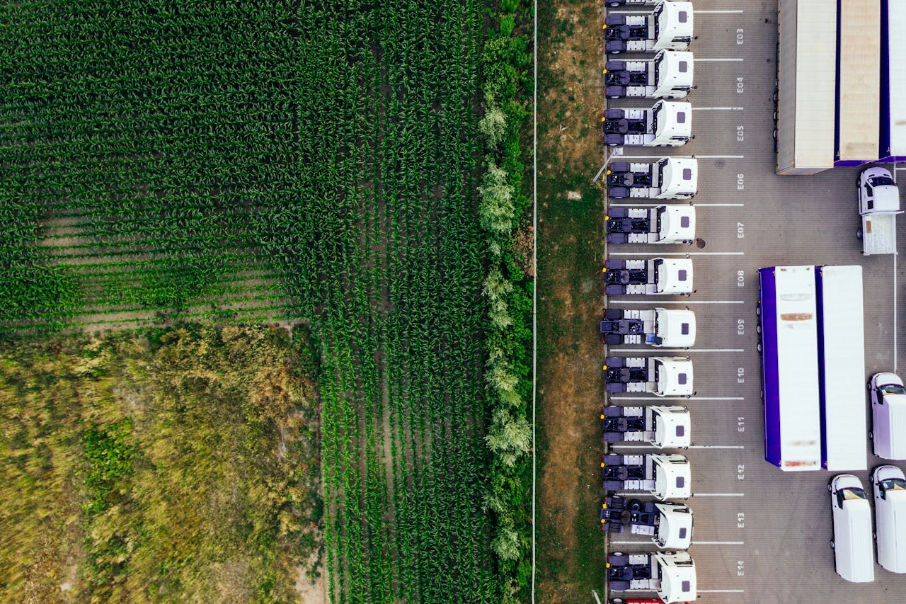 Drone shot of parked trucks next to a lush green cropland in Poznań, Poland.